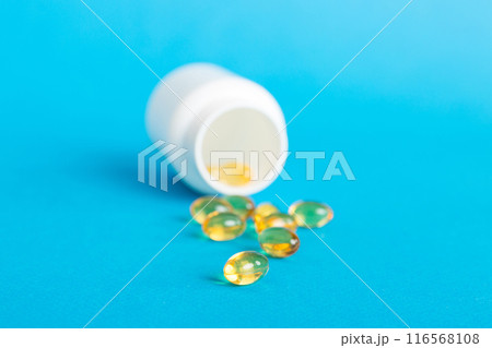 Soft gels pills with Omega-3 oil spilling out of pill bottle close-up. Gel capsules bottle white surface. Omega 3, multivitamins, Calcium, antibiotics. Health. Immunity 116568108