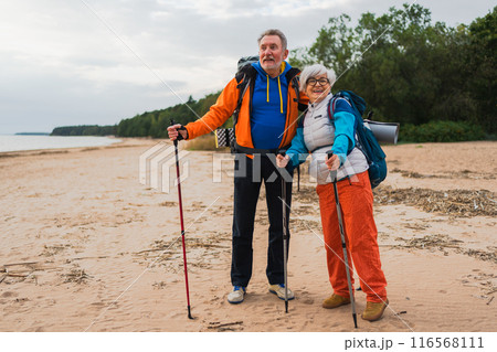 Hiking tourism adventure. Senior couple man woman enjoying outdoor recreation hiking on beach. Happy old people backpackers hikers enjoy walking hike trekking tourism active vacation beauty of nature Hiking tourism adventure. Senior couple man woman enjoying outdoor recreation hiking on beach. Happy old people backpackers hikers enjoy walking hike trekking tourism active vacation beauty of nature 116568111