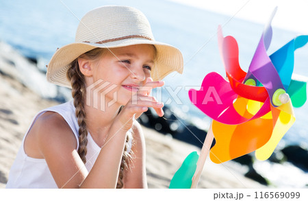 Girl with windmill on sea in summer 116569099