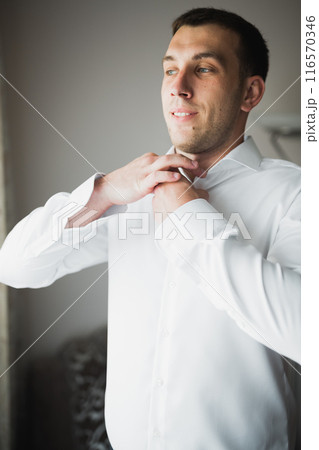 Grooms morning preparation. Handsome man getting dressed and preparing for the wedding 116570346