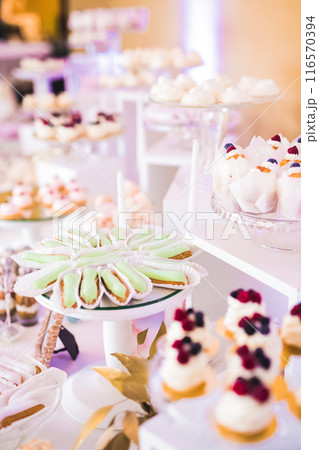 Delicious and tasty dessert table with cupcakes and shots at reception closeup Delicious and tasty dessert table with cupcakes and shots at reception closeup 116570394