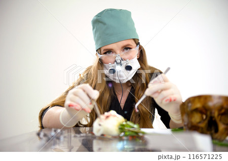 Operation on the layout . Young woman learning to operate on a flower on a rose using a scalpel and an injection 116571225