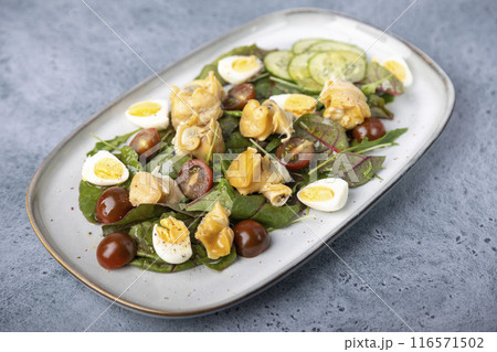 Warm salad with rapan (snails), tomatoes, cucumbers, leafy vegetables, quail eggs and olive oil. Traditional seafood salad. Close-up, selective focus. 116571502