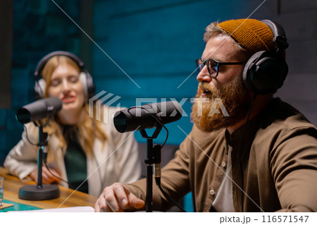 Podcast hosts engage in creative discussions in a studio setting while wearing headphones 116571547