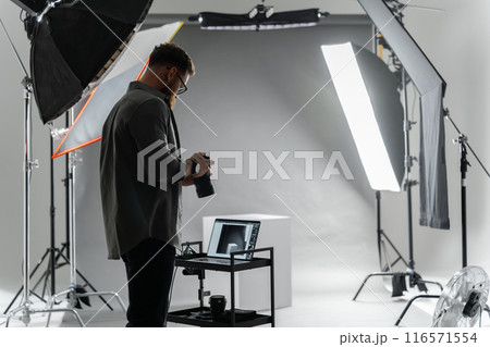 A photographer in a studio focuses on adjusting camera settings for the perfect shot A photographer in a studio focuses on adjusting camera settings for the perfect shot 116571554