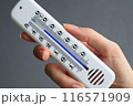 A womans hand with a plastic mercury thermometer shows high air temperature in Celsius outdoors in the shade. more than 36 degrees. 116571909