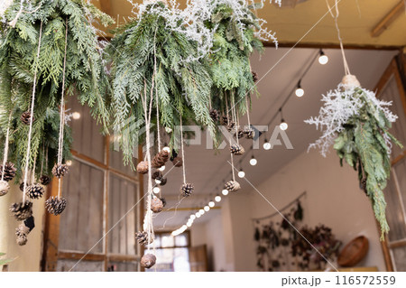 Festive Christmas Hanging Greenery with Pinecones and Lights in Cozy Rustic Setting Festive Christmas Hanging Greenery with Pinecones and Lights in Cozy Rustic Setting 116572559