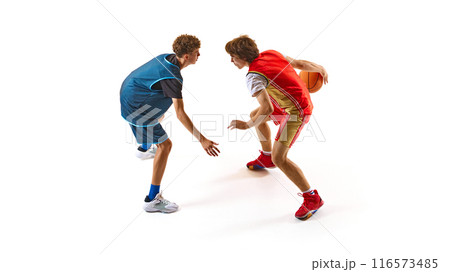 Two basketball players in action, one wearing blue jersey and other in red, as they prepare for one-on-one showdown. 116573485