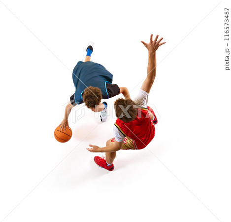 Basketball player in blue tries to outmaneuver defender in red, encapsulating thrill of game against white studio background. Aerial view. Basketball player in blue tries to outmaneuver defender in red, encapsulating thrill of game against white studio background. Aerial view. 116573487