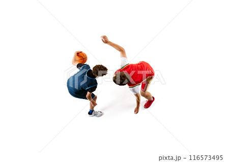 Dynamic shot of two young basketball athletes training their skills against white studio background. Aerial view. 116573495