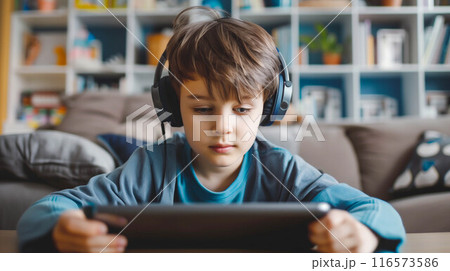 Boy watching video with headphone on tablet computer. Boy watching video with headphone on tablet computer. 116573586