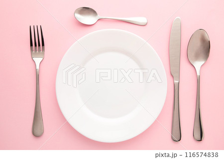 Table setting with white plates, and cutlery - fork, spoon and knife. Shot from above. Copy space on empty plate. 116574838