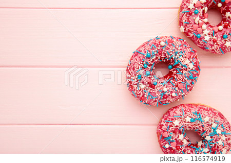 Donuts with icing on pink wooden background. Sweet donuts. Glazed donut. Donuts with icing on pink wooden background. Sweet donuts. Glazed donut. 116574919