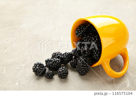 Blackberries in yellow cup on a grey background. Macro image. Blackberries in yellow cup on a grey background. Macro image. 116575104