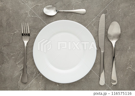 Table setting with white plates, and cutlery - fork, spoon and knife. Shot from above. Copy space on empty plate. Table setting with white plates, and cutlery - fork, spoon and knife. Shot from above. Copy space on empty plate. 116575116