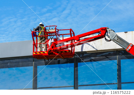 Elevated pedestrian overground tunnel facade painting using a telescopic boom lift with a basket 116575222