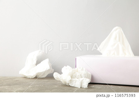 Box with paper tissues and used crumpled napkins on grey background 116575393