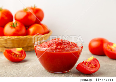 Tomato ketchup sauce in a bowl with tomatoes on grey wooden background. View from above. Tomato ketchup sauce in a bowl with tomatoes on grey wooden background. View from above. 116575444