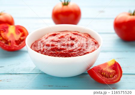 Tomato ketchup sauce in a bowl with tomatoes on blue wooden background. View from above. 116575520