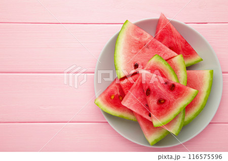 Fresh ripe striped sliced watermelon in the plate on pink wooden background. 116575596