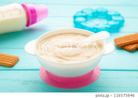 Bowl with baby food with toys on blue background 116575646