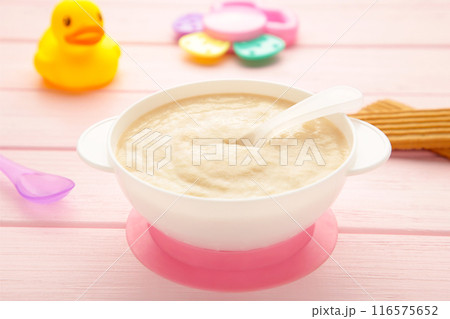 Bowl with baby food with toys on pink background 116575652