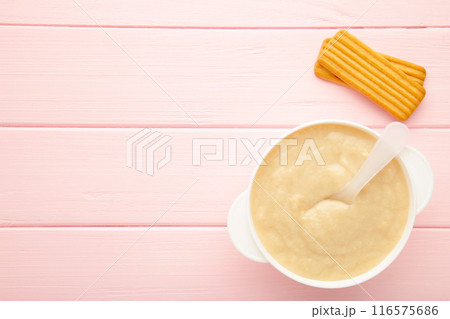 Bowl with baby food with biscuits on pink background Bowl with baby food with biscuits on pink background 116575686