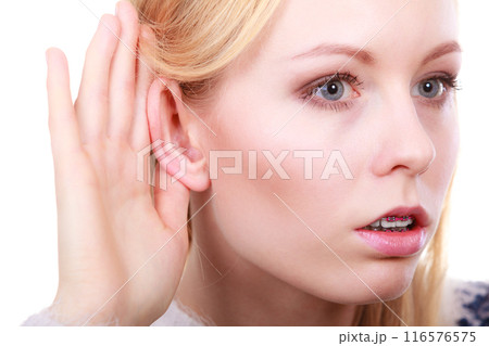 Woman listening carefully with hand close to ear Woman listening carefully with hand close to ear 116576575