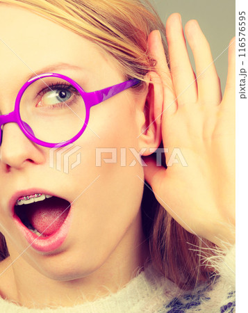 Woman listening carefully with hand close to ear Woman listening carefully with hand close to ear 116576595