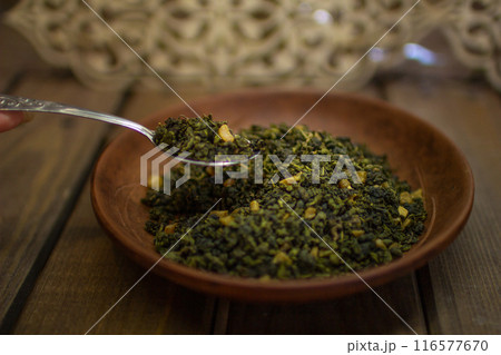 A clay plate with green fruit tea stands on a wooden table. 116577670