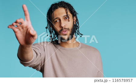 Assertive Middle Eastern man doing stop hand gestures. Annoyed BIPOC person doing firm halt sign gesturing, wishing to end concept, isolated over blue studio background, camera B 116578957