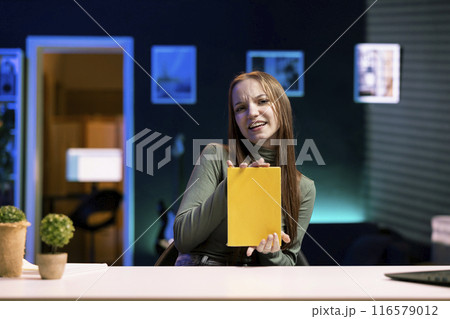 Gen Z influencer doing literature critique for online streaming channel audience. Young media star commenting on new book release significance, doing video essay for viewers in studio 116579012