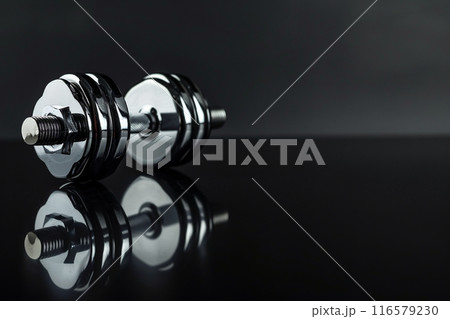 反射する表面に置かれているメタリックなダンベルとコピースペース 116579230