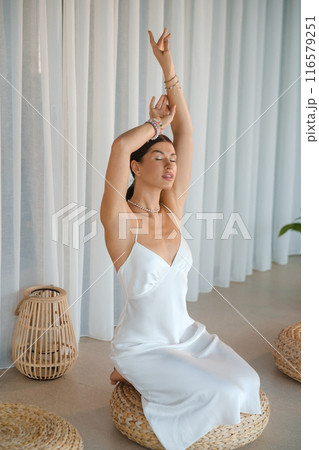 Girl in white dress does aesthetic gymnastics in gym. Girl doing yoga in the gym 116579251