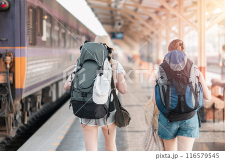 Two young backpackers with large backpacks walking on a train station platform, ready for their next travel adventure. 116579545