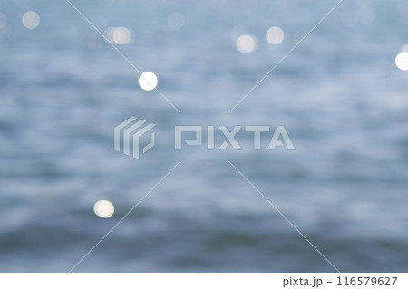 Sea view on a sunny summer day. Seascape. Sea landscape with blue sea water surface, small ripples and white bokeh spots with highlights of reflecting of the sun. Blurred abstract natural background Sea view on a sunny summer day. Seascape. Sea landscape with blue sea water surface, small ripples and white bokeh spots with highlights of reflecting of the sun. Blurred abstract natural background 116579627