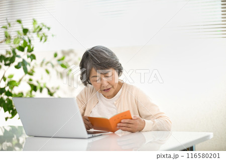年金手帳を見るシニア女性 116580201