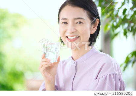 リビングで水を飲む笑顔のミドル女性 リビングで水を飲む笑顔のミドル女性 116580206