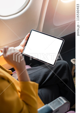 Business professional using a tablet with a blank screen on an airplane, showcasing in-flight productivity and travel technology. Business professional using a tablet with a blank screen on an airplane, showcasing in-flight productivity and travel technology. 116580483