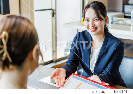 資料を見せて説明するセールスレディ― 116580743