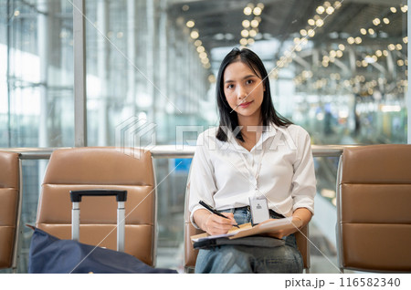 An attractive Asian businesswoman is working while sitting at a waiting seat in the airport terminal An attractive Asian businesswoman is working while sitting at a waiting seat in the airport terminal 116582340