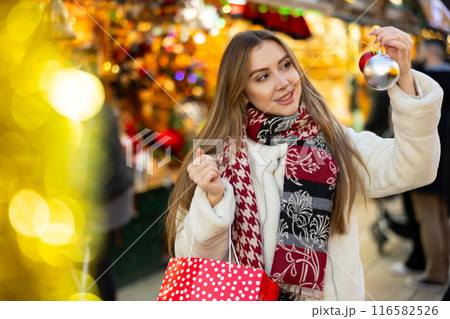Portrait of girl with gift bag choosing Christmas tree balls Portrait of girl with gift bag choosing Christmas tree balls 116582526