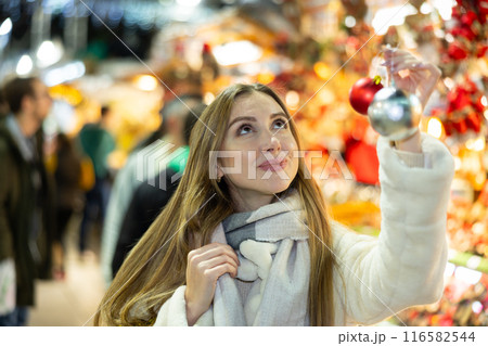 Portrait of dreamily happy girl with Christmas balls in her hands at a street fair in evening Portrait of dreamily happy girl with Christmas balls in her hands at a street fair in evening 116582544