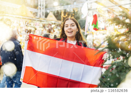 Happy girl with Austrian flag waving at New Year fair 116582636
