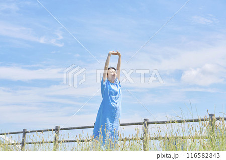 屋外で伸びをする女性 116582843