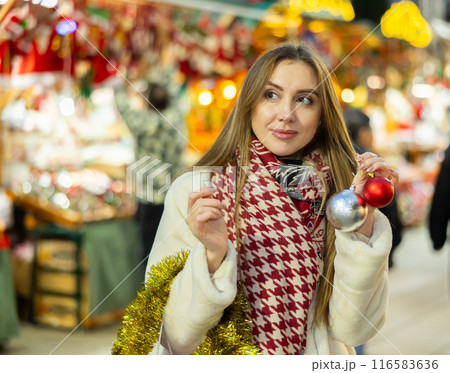 Young woman has purchased decorations for Christmas tree, tinsel and colorful balls 116583636