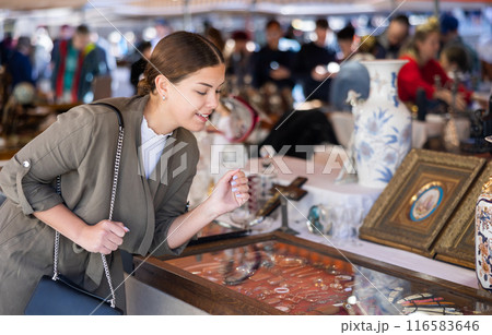Young woman looking at vintage items at flea market Young woman looking at vintage items at flea market 116583646