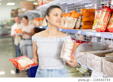 Young woman chooses noodles in store Young woman chooses noodles in store 116583734