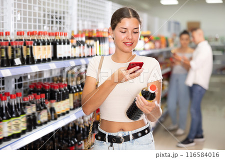 Girl using smartphone to scan barcode on soy sauce in store Girl using smartphone to scan barcode on soy sauce in store 116584016