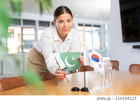 Female employee of the delegation sets flags of countries of South Korea and Pakistan on the table before start of negotiations 116584123
